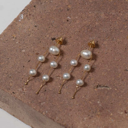 Brinco ouro 18k 5 perolas apoiado em fundo de pedra