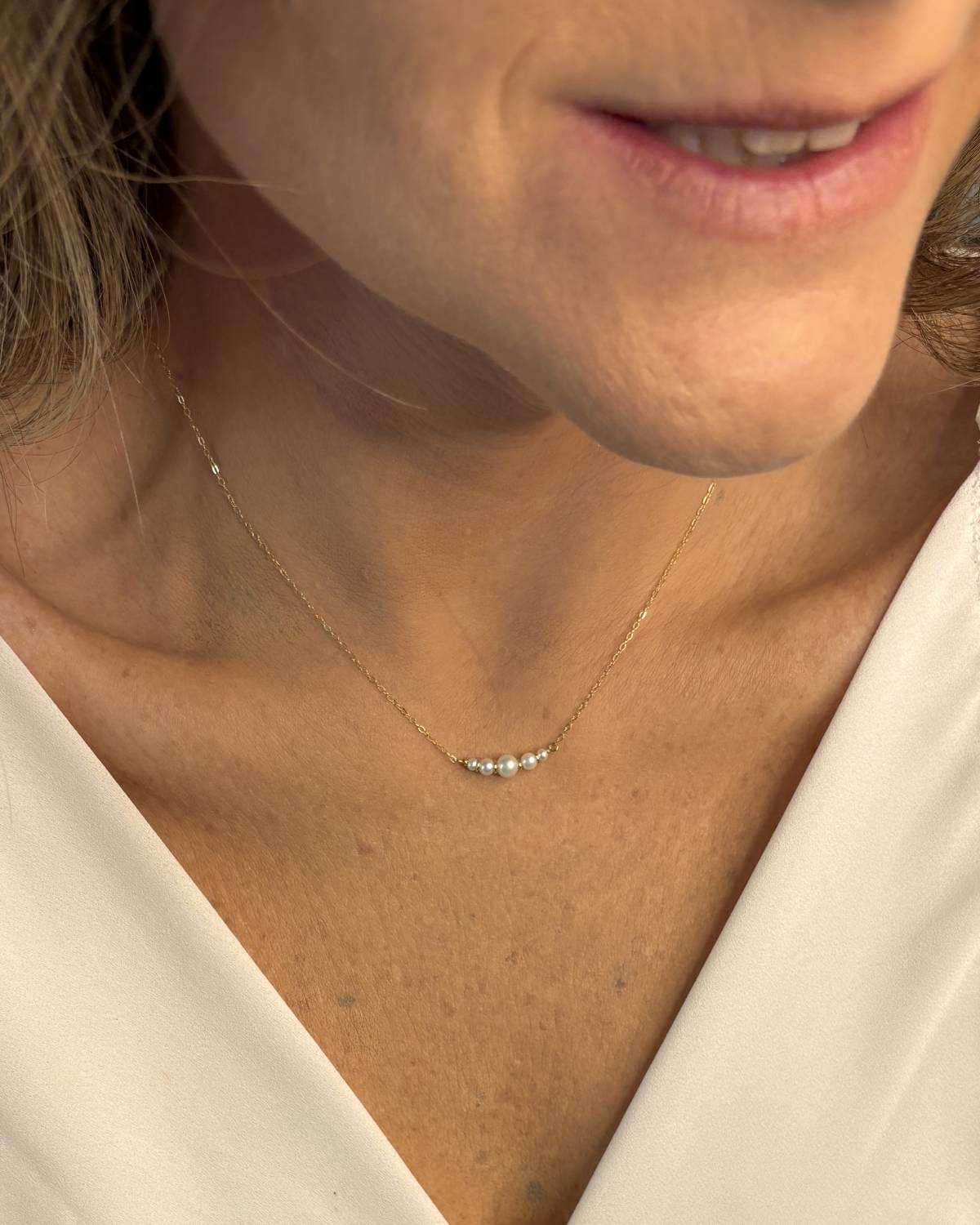 Colar pérolas naturais e ouro 18k meia-lua usado no pescoço com blusa branca