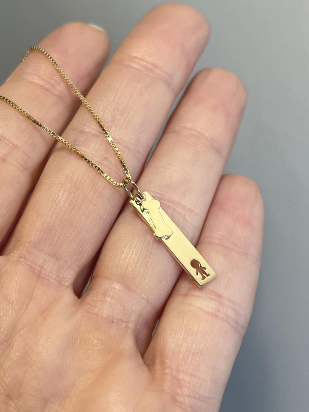 Mulher segurando na palma da mão Colar Placa Menino Osso Ouro 18k