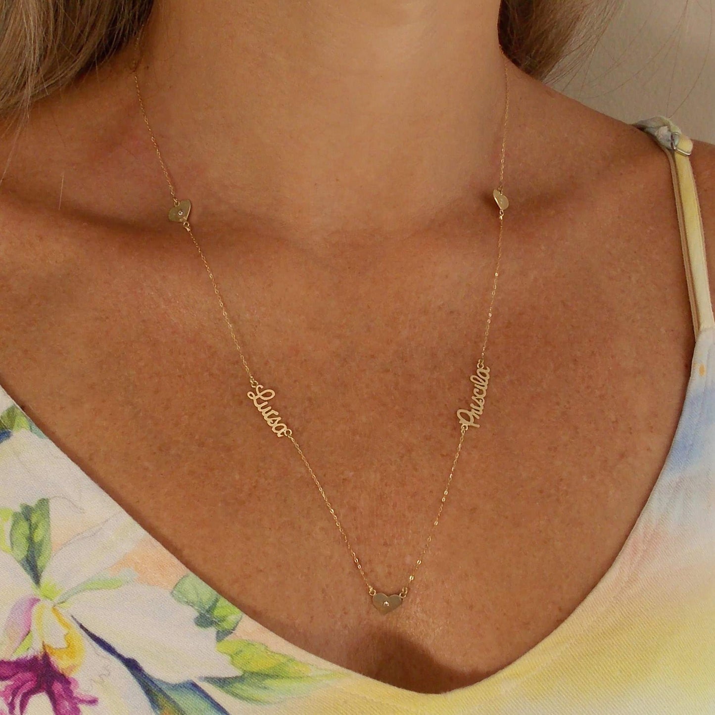 Colar de ouro com 2 nomes e 3 corações no colo
