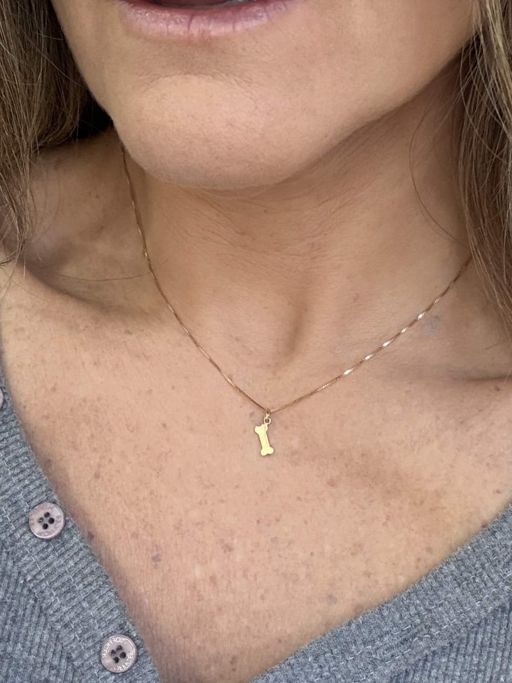 mulher de 44 anos levemente de lado usando Colar Patinha Ouro 18k 