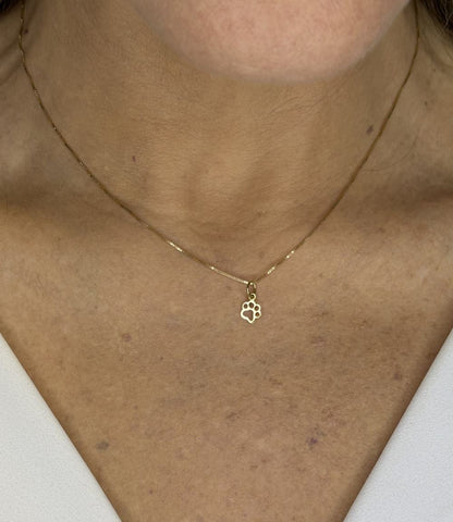 Mulher vestindo colar com pingente patinha 6mm em ouro 18k