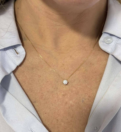 Mulher de 43 anos de camisa azul clara usando o colar Ponto de Luz Moissanite de 5mm Ouro 18k da Marilia Chiele Joias