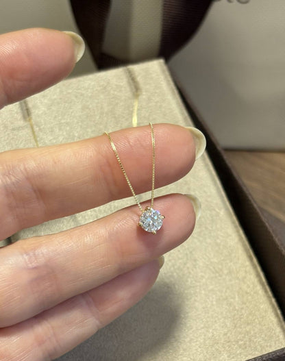 Mão feminina segurando o colar Ponto de Luz Moissanite de 5mm Ouro 18k da Marilia Chiele Joias