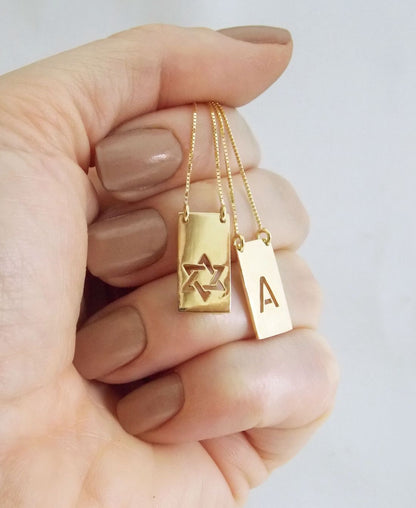 Mulher segurando na mão Escapulário Estrela de Davi e Letra A Ouro 18k