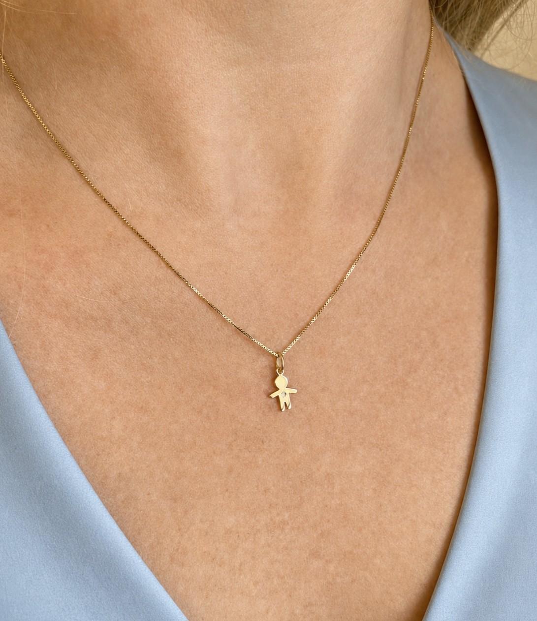 Mulher de 44 anos usando colar com um pingente menino em ouro 18k com 1 brilhante de meio ponto