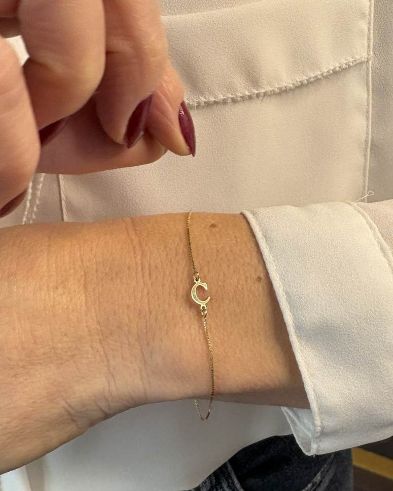 pulseira de letra em ouro 18k no pulso feminino