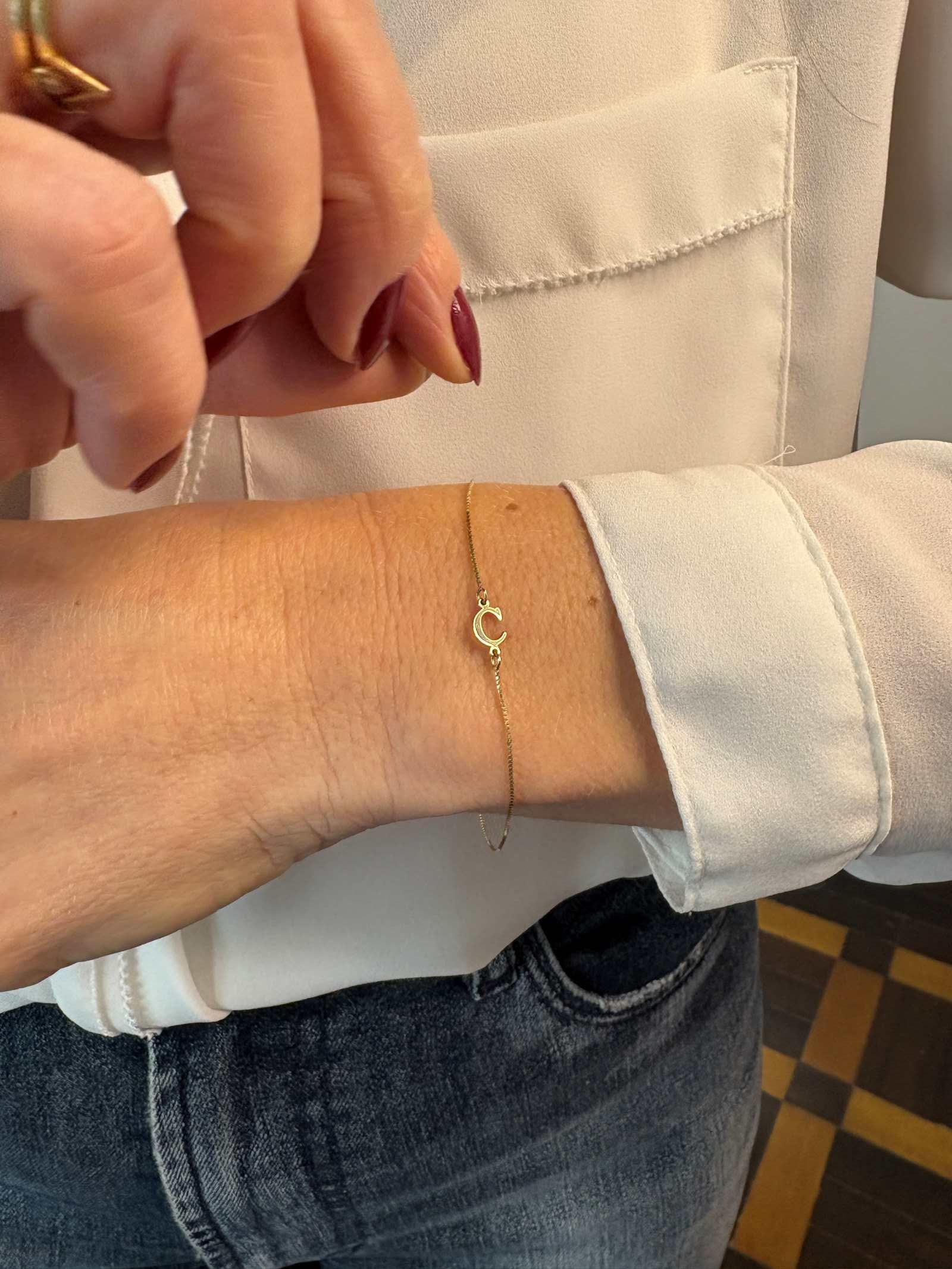 pulseira de letra em ouro 18k no pulso feminino