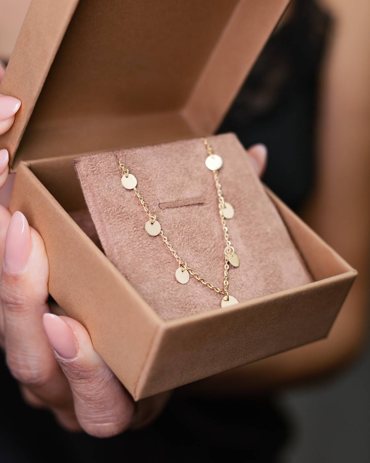 Mulher segurando embalagem com Colar ouro 18k corrente bailarina e medalhas