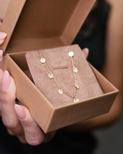 Mulher segurando embalagem com Colar ouro 18k corrente bailarina e medalhas